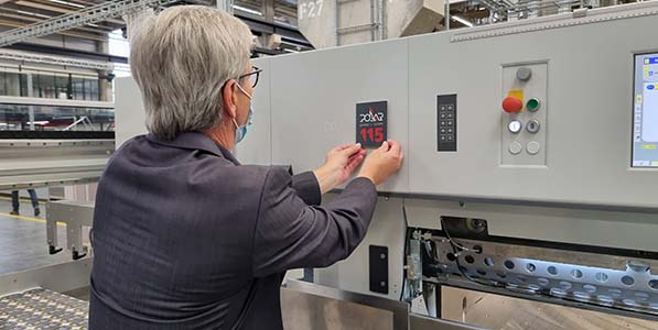 Head of Marketing Frank Mayer attaches the anniversary plaque to a cutting machine 